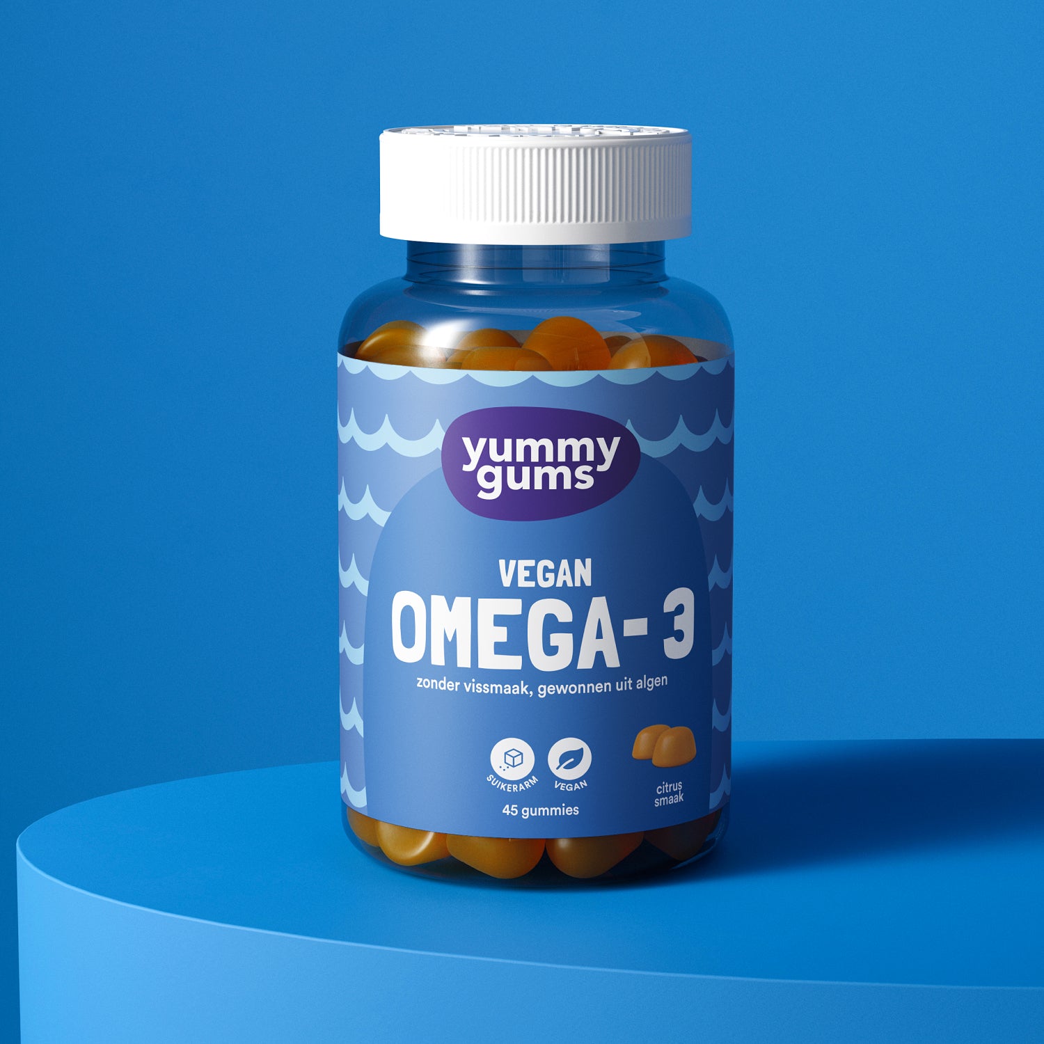 Een flesje Yummygums Omega-3 Vegan Gummies rust op een blauw oppervlak, met een blauw etiket met golvende en witte tekst die de oranje smaak, het veganistische DHA uit algenolie en de ingrediënten op basis van algen benadrukt.
