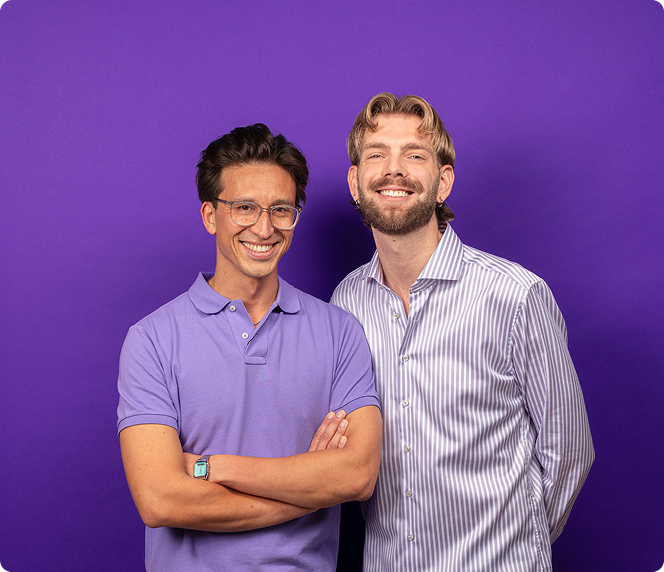 Twee mannen staan glimlachend voor een effen paarse achtergrond; de een draagt een bril en een paarse polo met gekruiste armen, terwijl de ander een gestreept button-up shirt draagt.